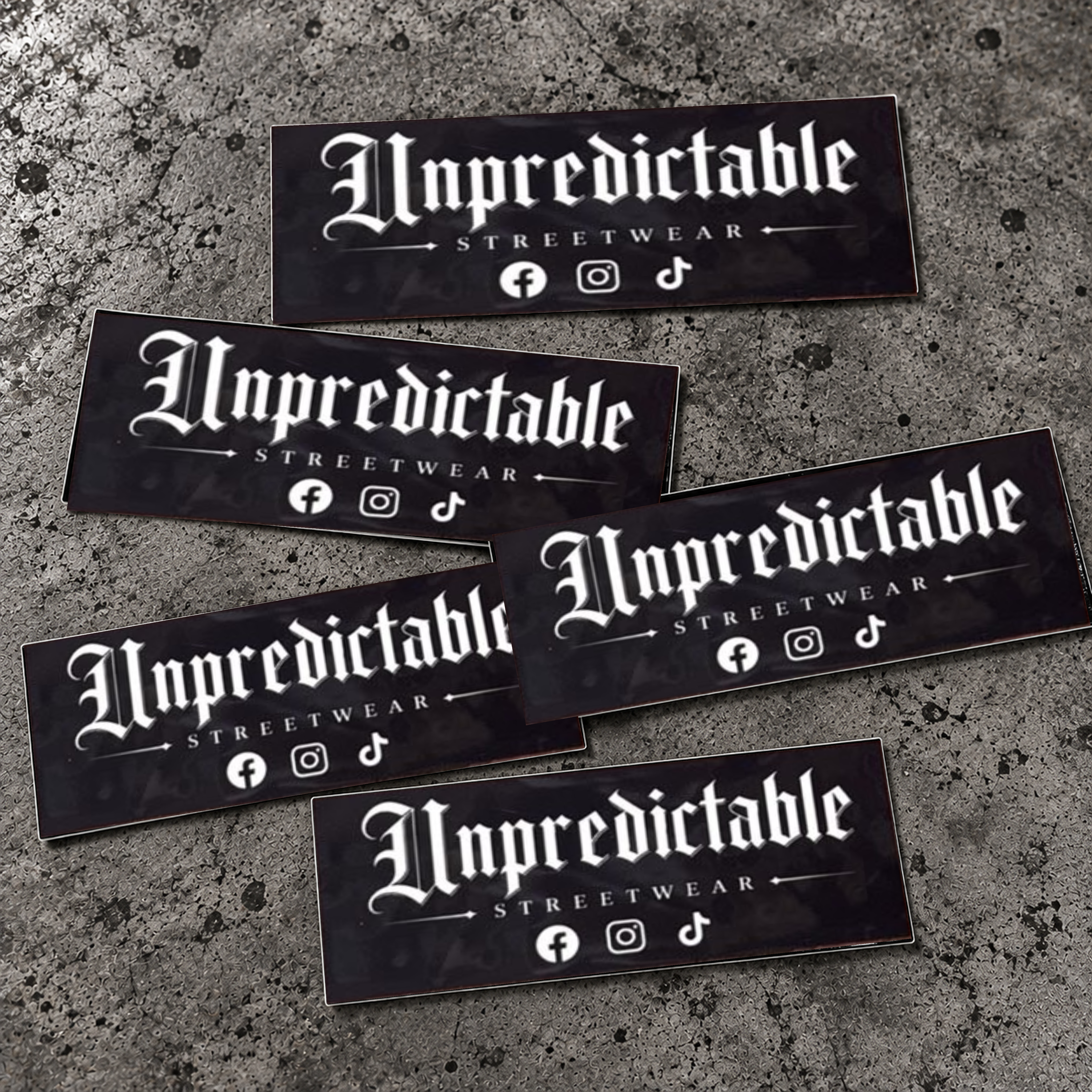 Unpredictable Streetwear 100x40mm stickers with Facebook, Instagram and TikTok icons on concrete