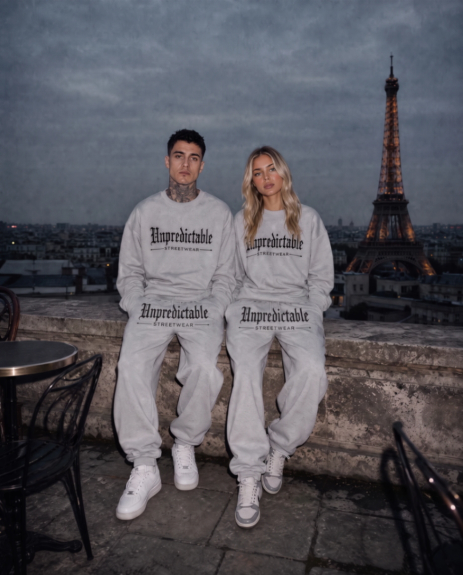 Two models wearing Unpredictable Streetwear grey embroidered crew necks and tracksuit bottoms on a Paris rooftop